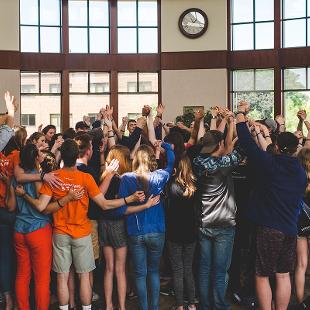 A group of Awakening students with their arms raised