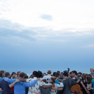 A group of students praying on the beach