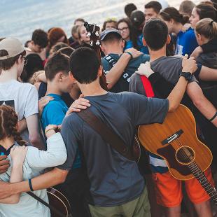 A group of students praying on the beach