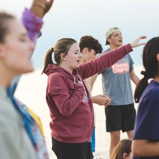 A female student singing with her arms raised