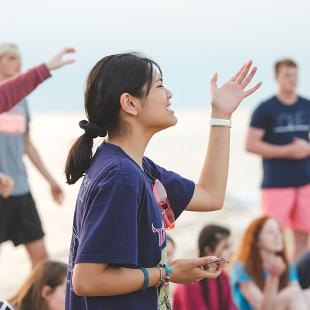 A female student singing with her arms raised