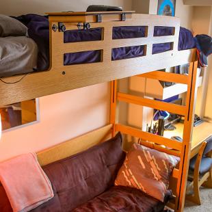 Student room in Phelps Residence Hall showing the bed lofted with a couch underneath.