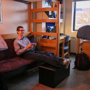 Student room in Phelps Residence Hall with student sitting on couch.