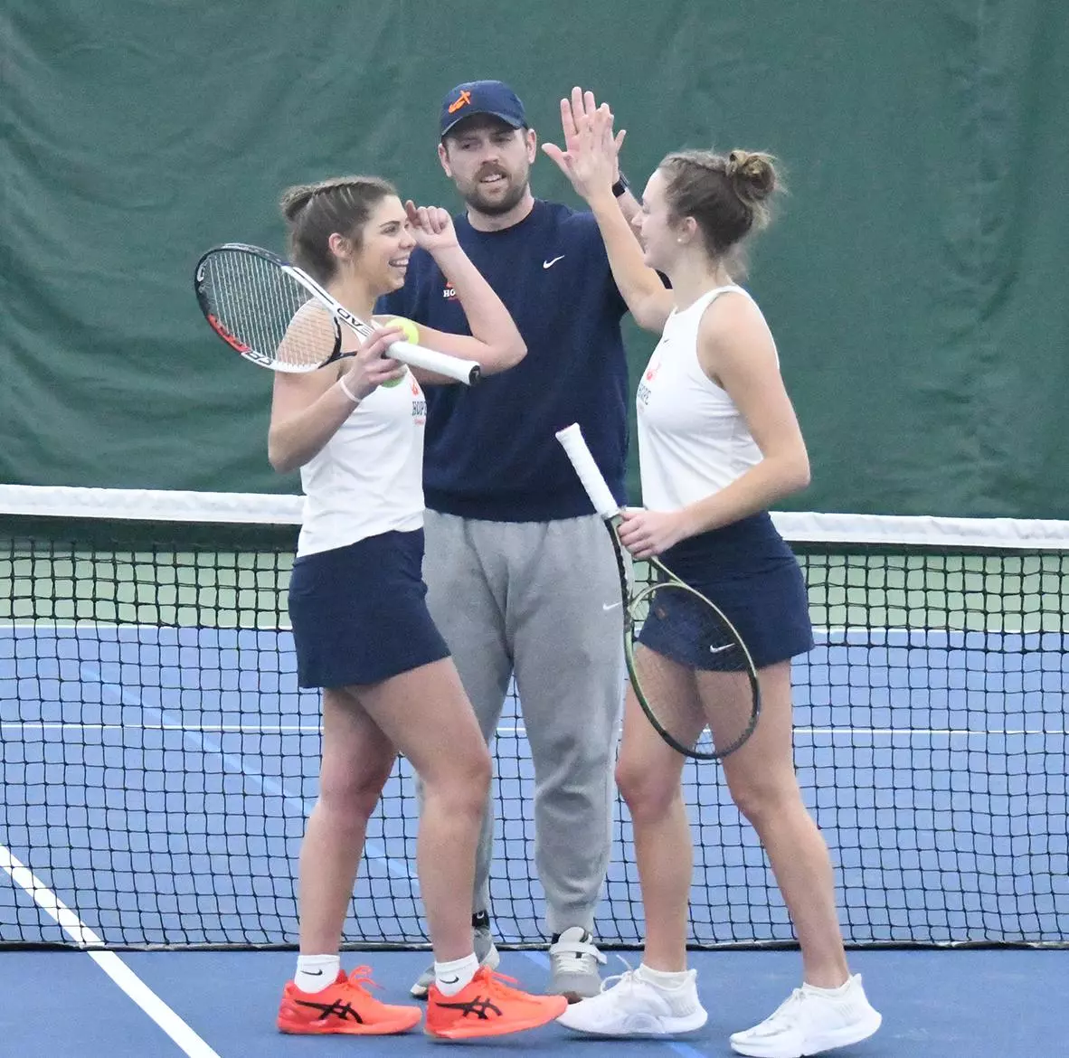 Hope tennis coach and a doubles team high-five during a break.